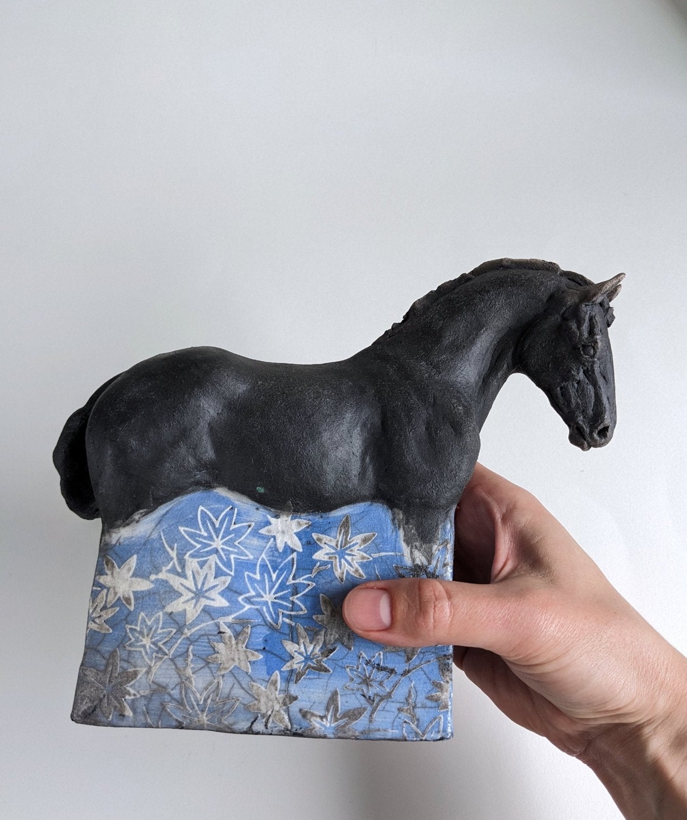Black ceramic horse with white and blue leaf decal design