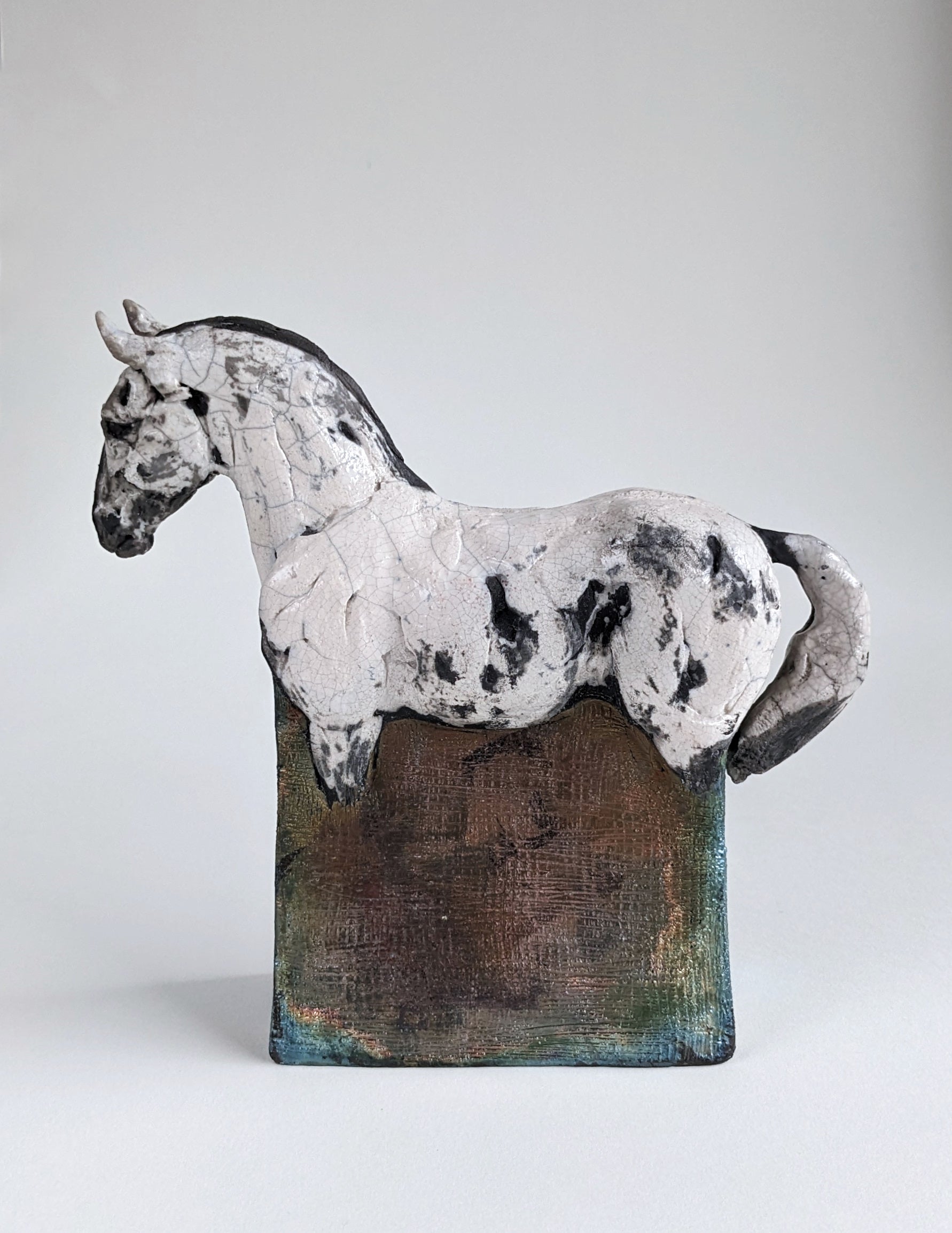 White and metallic ceramic horse sculpture in hand